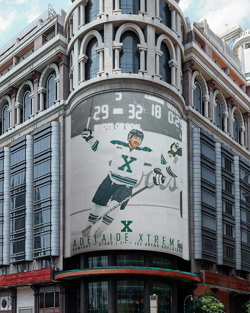 Large-format NHSL advertising wraps a city building with an Adelaide Xtreme player celebrating on the ice, showing the bold public campaign used to build team recognition and game-day interest.
