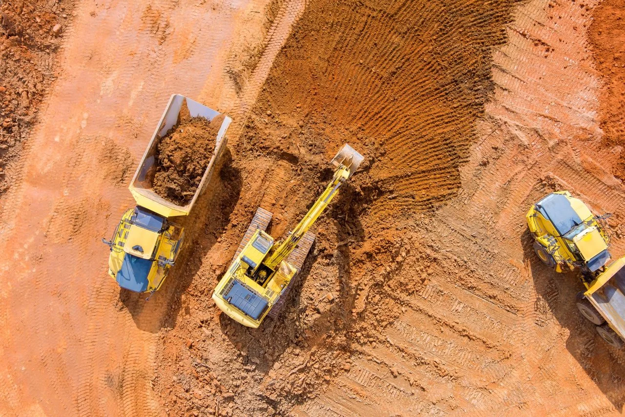 Aerial view of an excavator loading earth into a dump truck on a mining site, demonstrating Mine Services Holdings’ equipment capability and suitability for demanding civil and resource projects.
