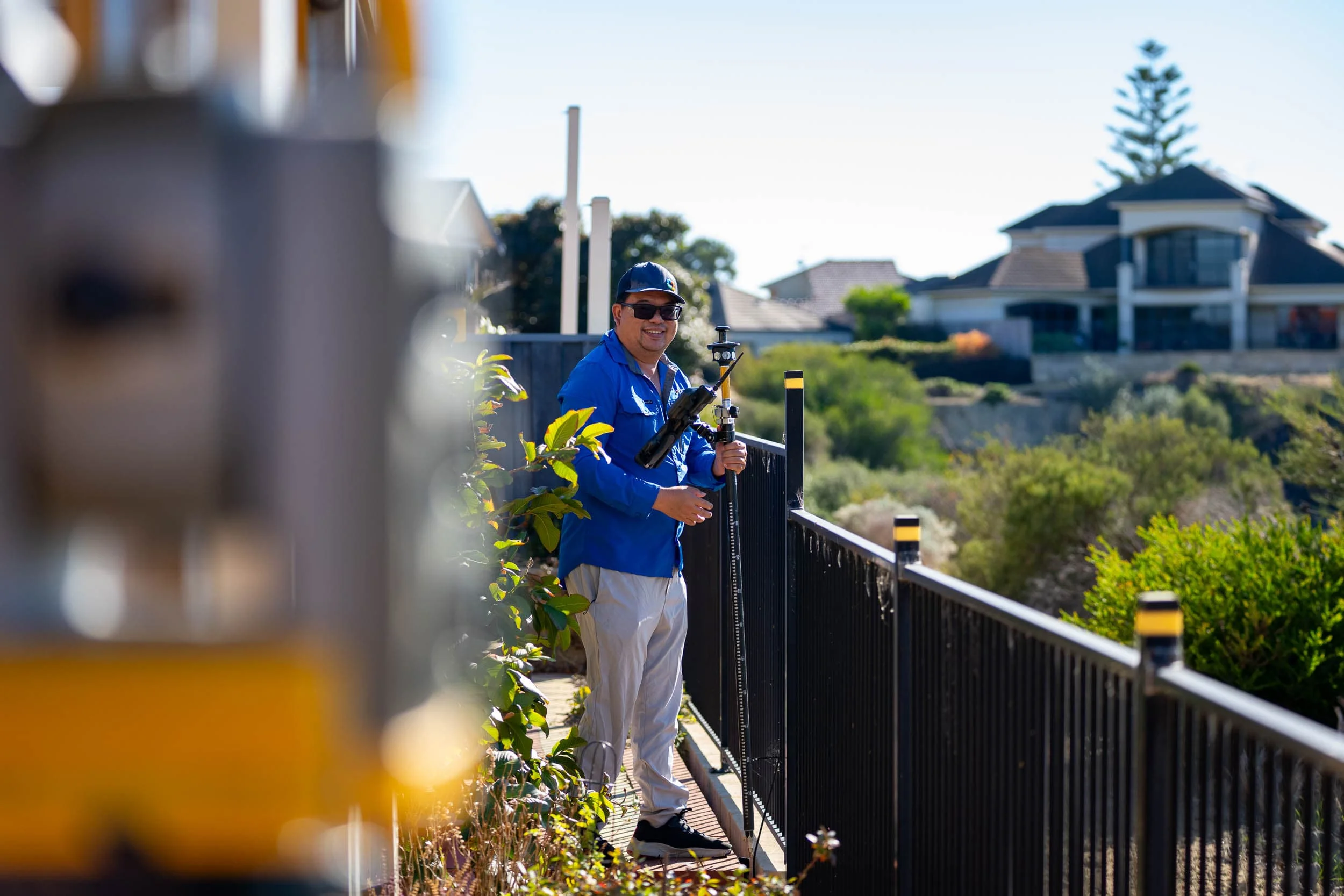 Perth Surveying team member uses surveying equipment beside a residential property, showing the practical field capability, local knowledge and dependable project support behind the business.