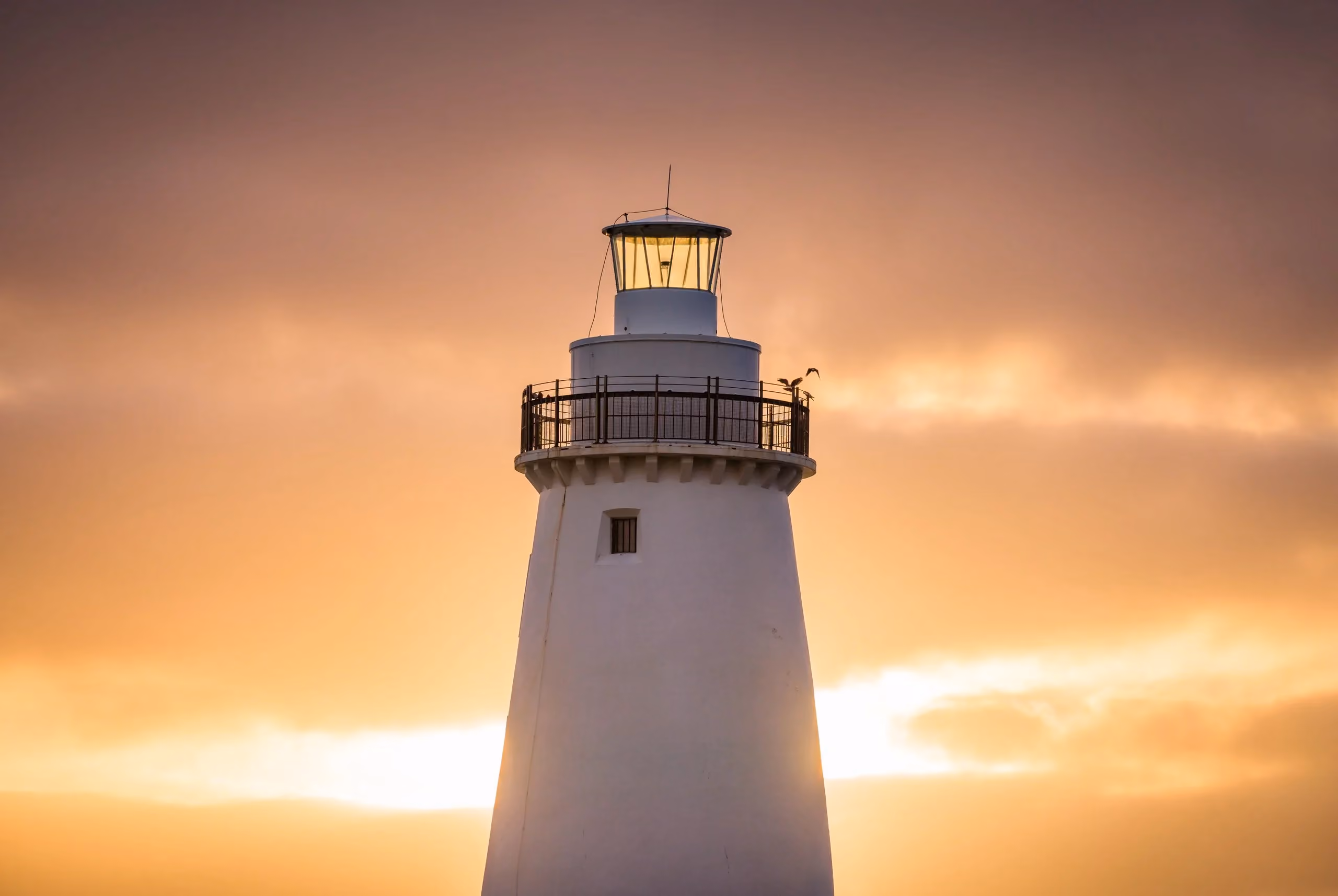 White lighthouse illuminated against a warm sunset sky, symbolising the clarity, guidance and trusted direction at the centre of People Leading Tribes’ founder-first brand.