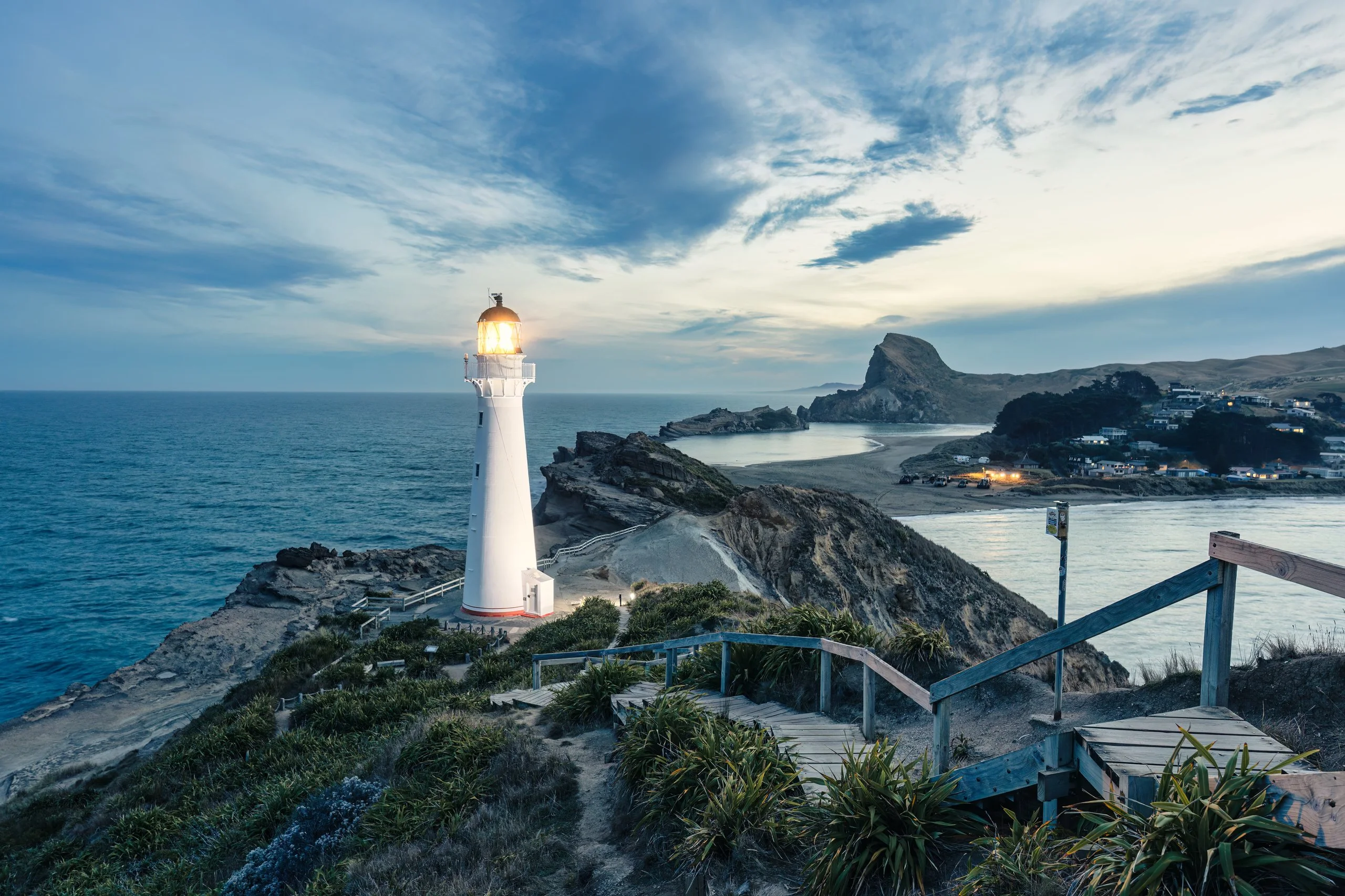 Coastal lighthouse glowing above a rugged shoreline at dusk, symbolising the clarity, experience and steady guidance People Leading Tribes offers founders navigating business growth.