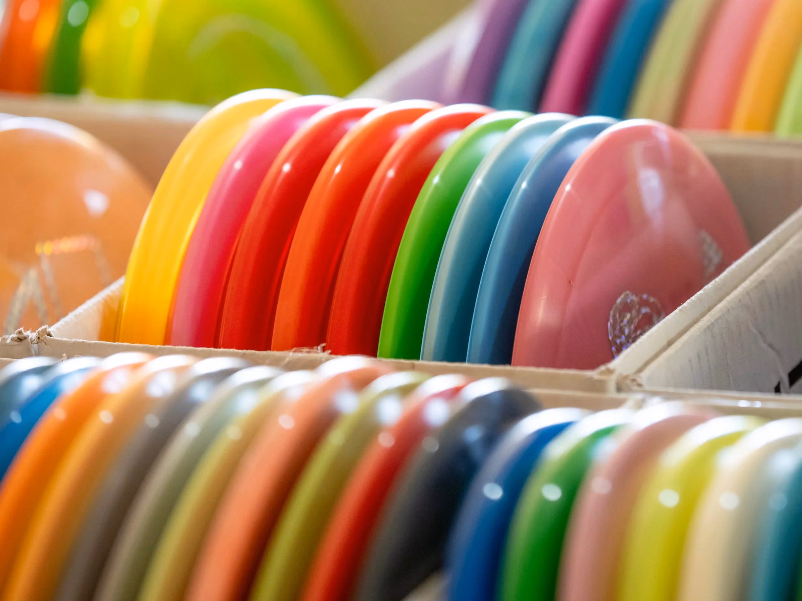 Rows of brightly coloured flying discs arranged in stock boxes, showing Flying Disc Store’s broad product range and the seasonal inventory behind its record sales campaign.