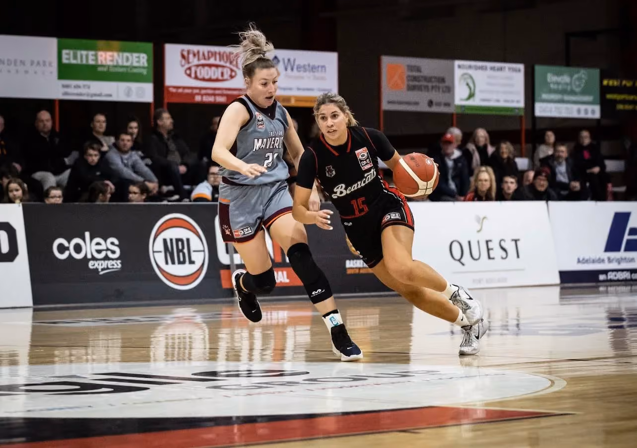 West Adelaide Bearcats player drives past a defender during an NBL1 game in front of a packed crowd, capturing the on-court intensity and public momentum behind the club’s championship campaign.