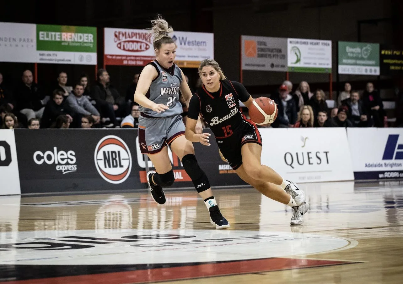 West Adelaide Bearcats player drives past a defender during an NBL1 game in front of a packed crowd, capturing the on-court intensity and public momentum behind the club’s championship campaign.