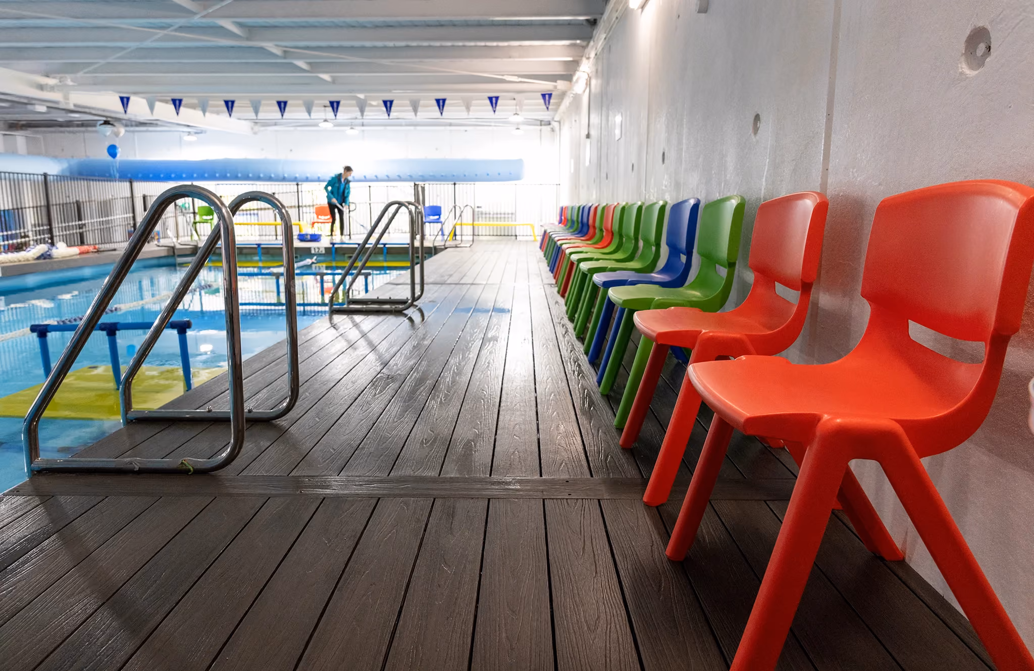 Indoor WaterPonyz swim school pool with colourful children’s chairs along the deck, showing the organised, family-friendly environment supporting a clear journey from parent enquiry to swimming lessons.