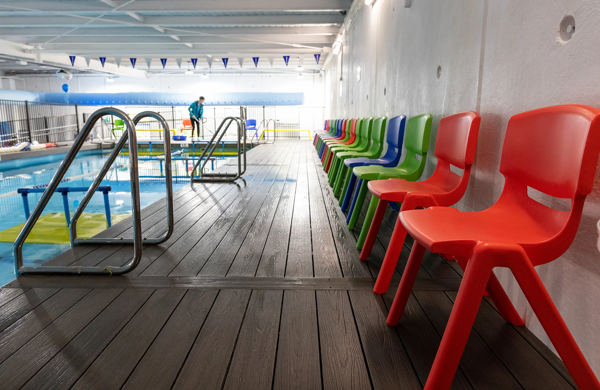 Indoor WaterPonyz swim school pool with colourful children’s chairs along the deck, showing the organised, family-friendly environment supporting a clear journey from parent enquiry to swimming lessons.