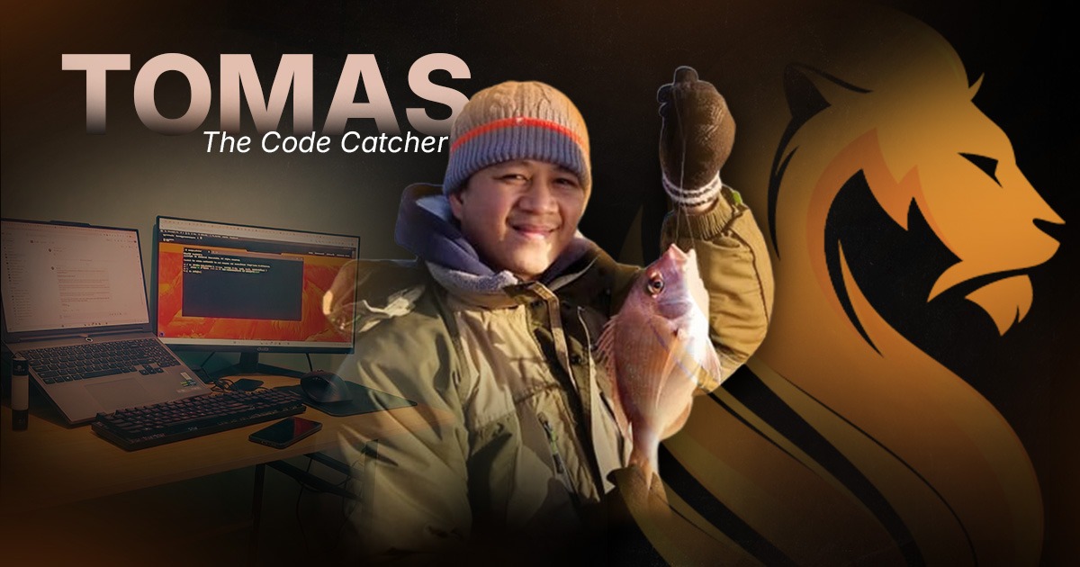 Tomas, Wandering Lion’s Code Catcher, holding a fish beside his web development and IT workspace.