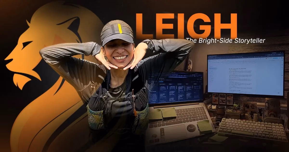 Leigh, Wandering Lion’s Bright-Side Storyteller, smiling beside her copywriting workspace and research screens.