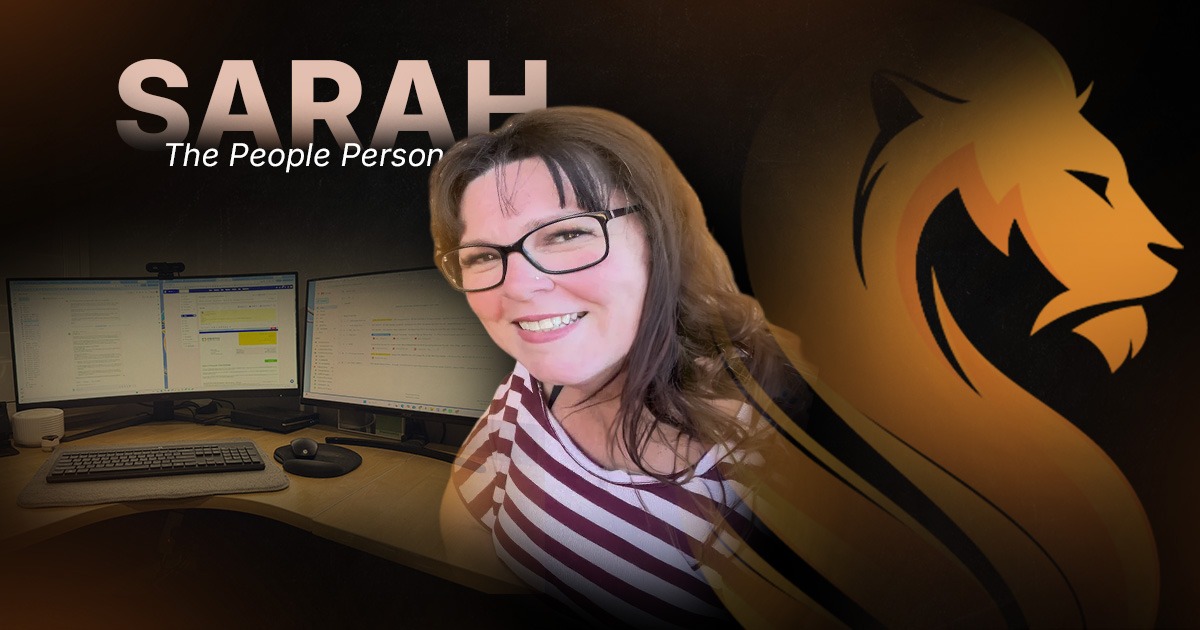 Sarah, Wandering Lion’s People Person, smiling beside the remote systems she uses to support the team.