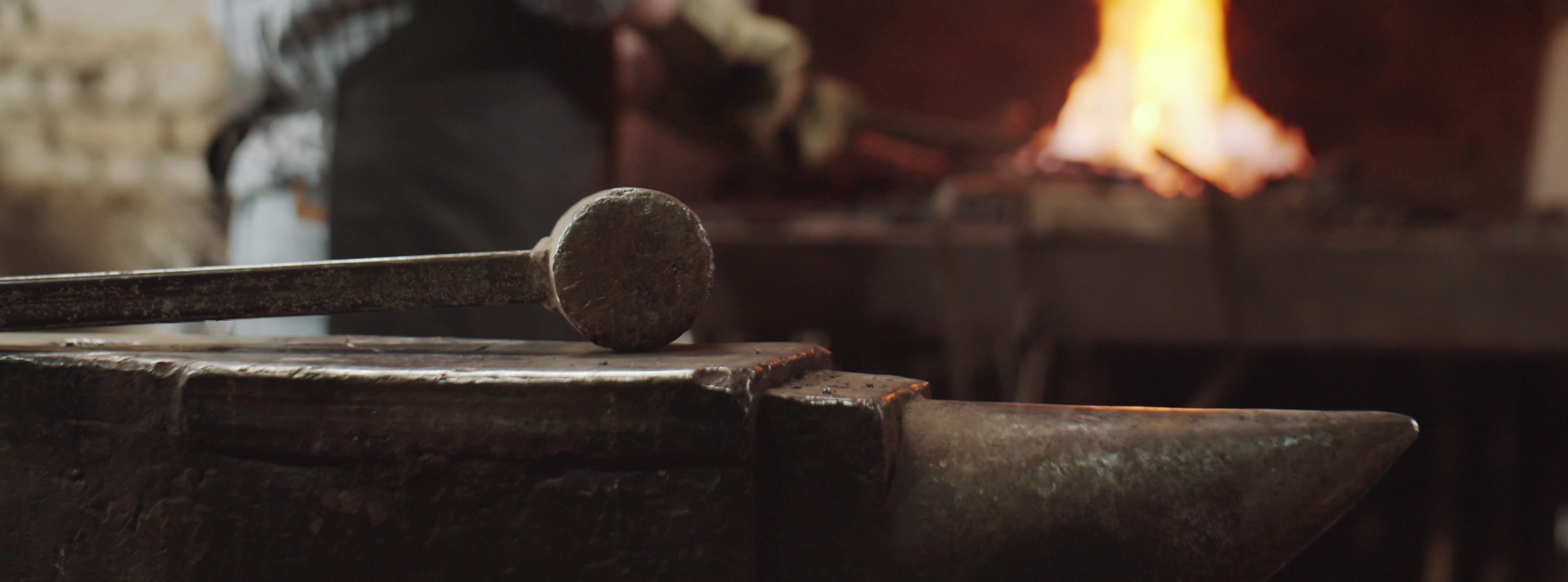 Blacksmith hammer resting on anvil with forge fire in background