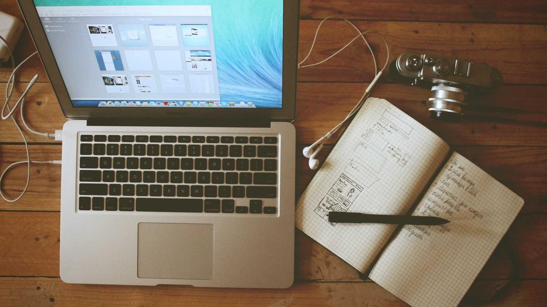 Business owner working from a laptop with a notebook and coffee at their desk