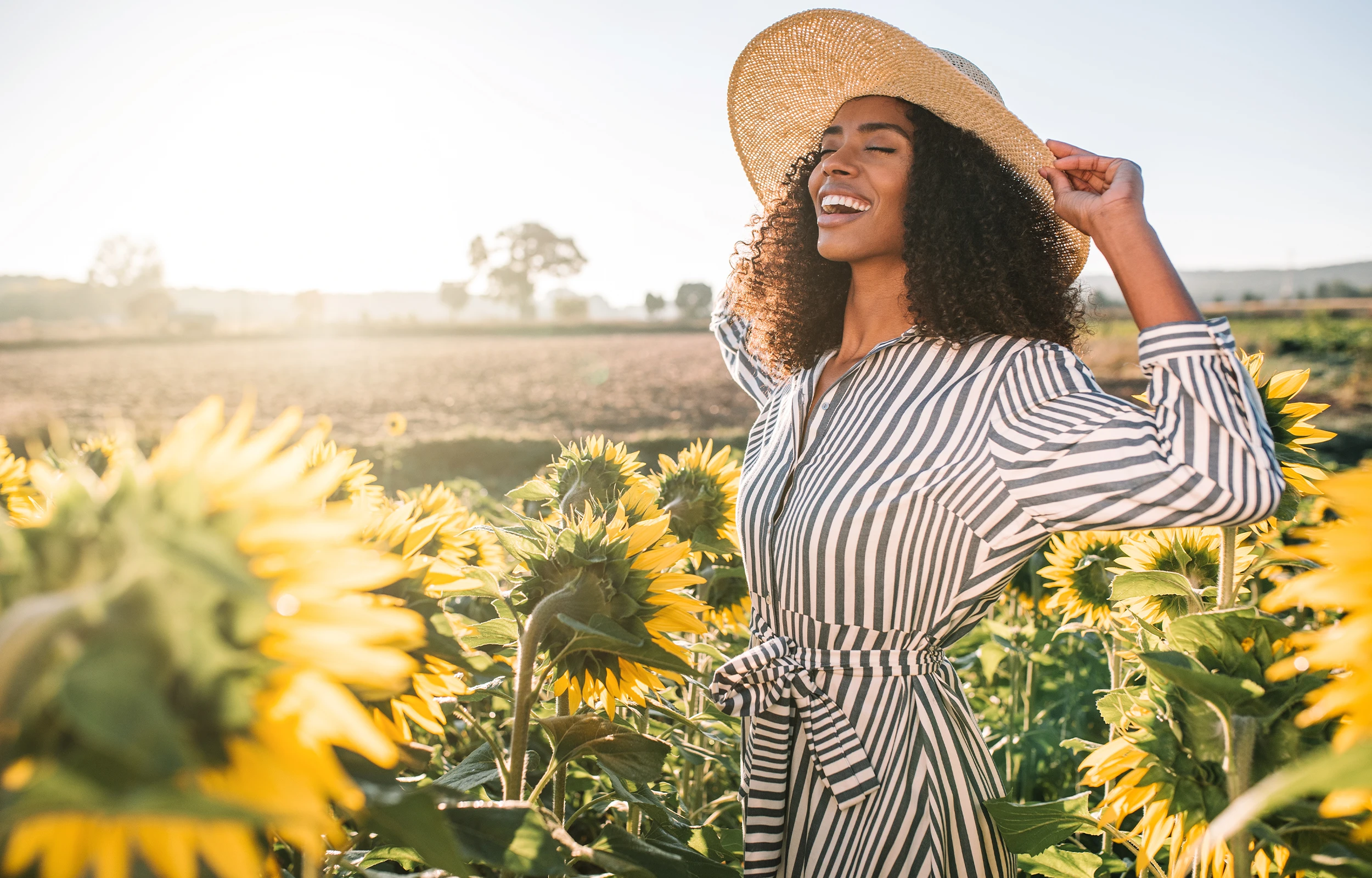 Woman laughing in a sunflower field, representing energy and long-term vitality