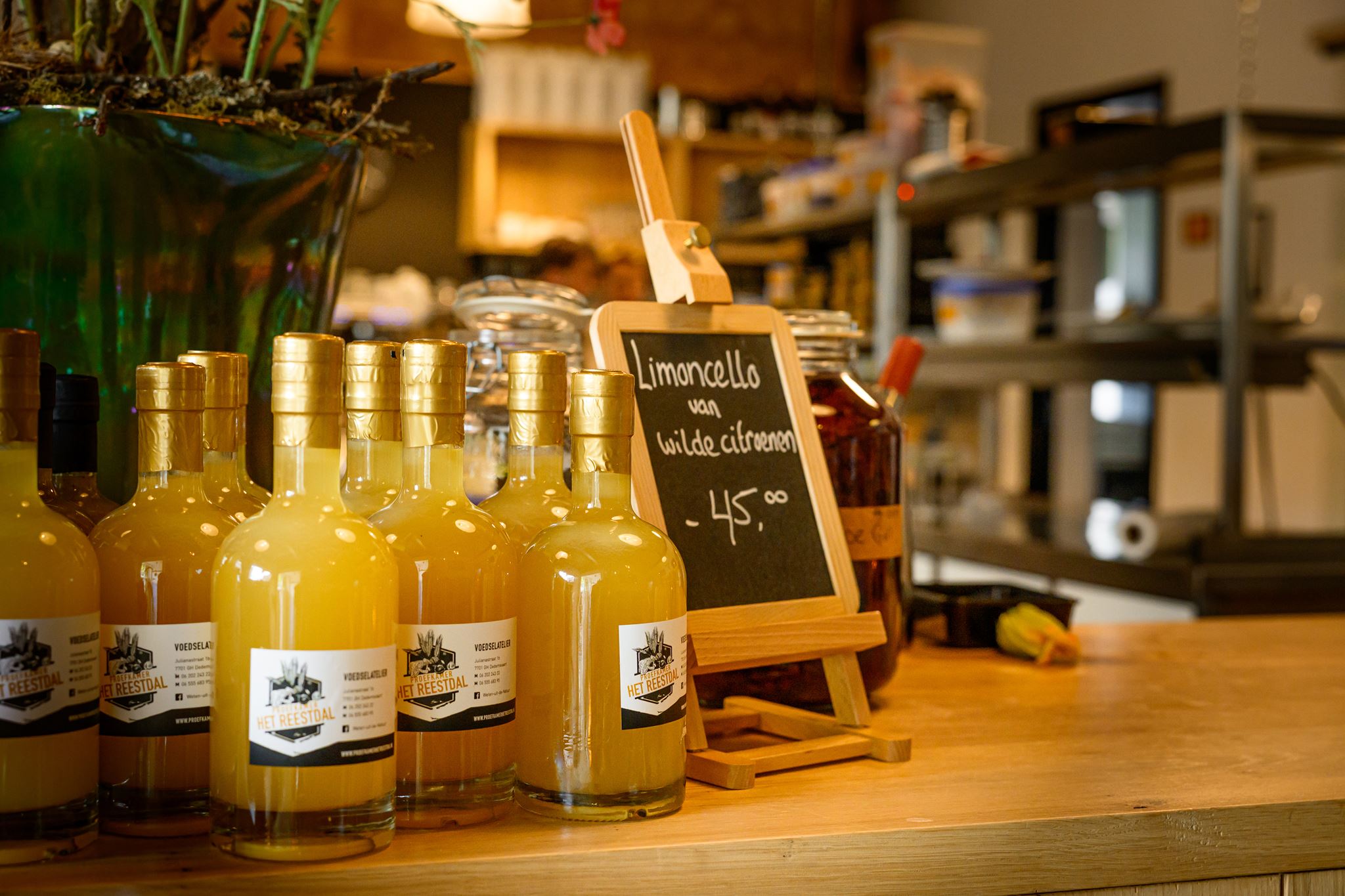 Bottles of limoncello with gold caps on a wooden counter next to a small chalkboard sign.