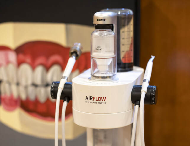 EMS AIRFLOW handpiece in front of a model of teeth