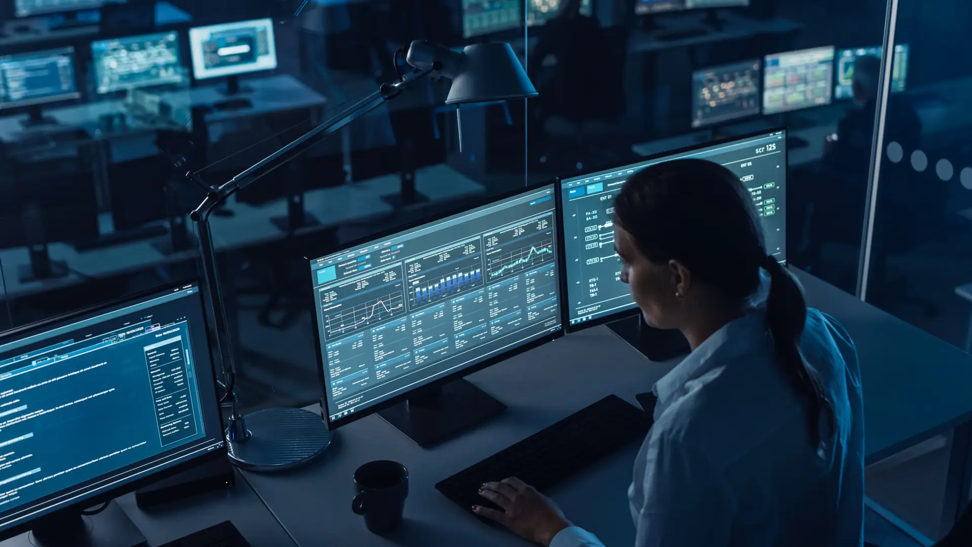 Operator monitoring energy trading dashboards on several screens in a control room at night