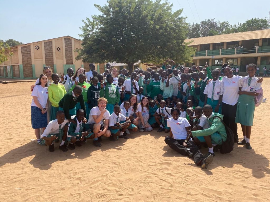 The students and children from the school are grouped together for a photo.