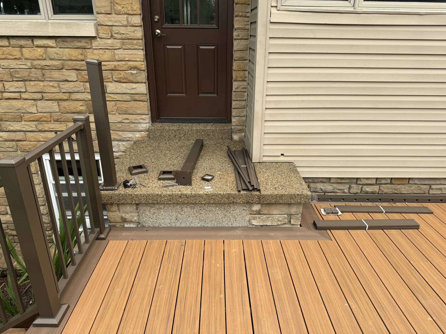 Before: unfinished composite deck step with loose railing hardware and bare wood riser