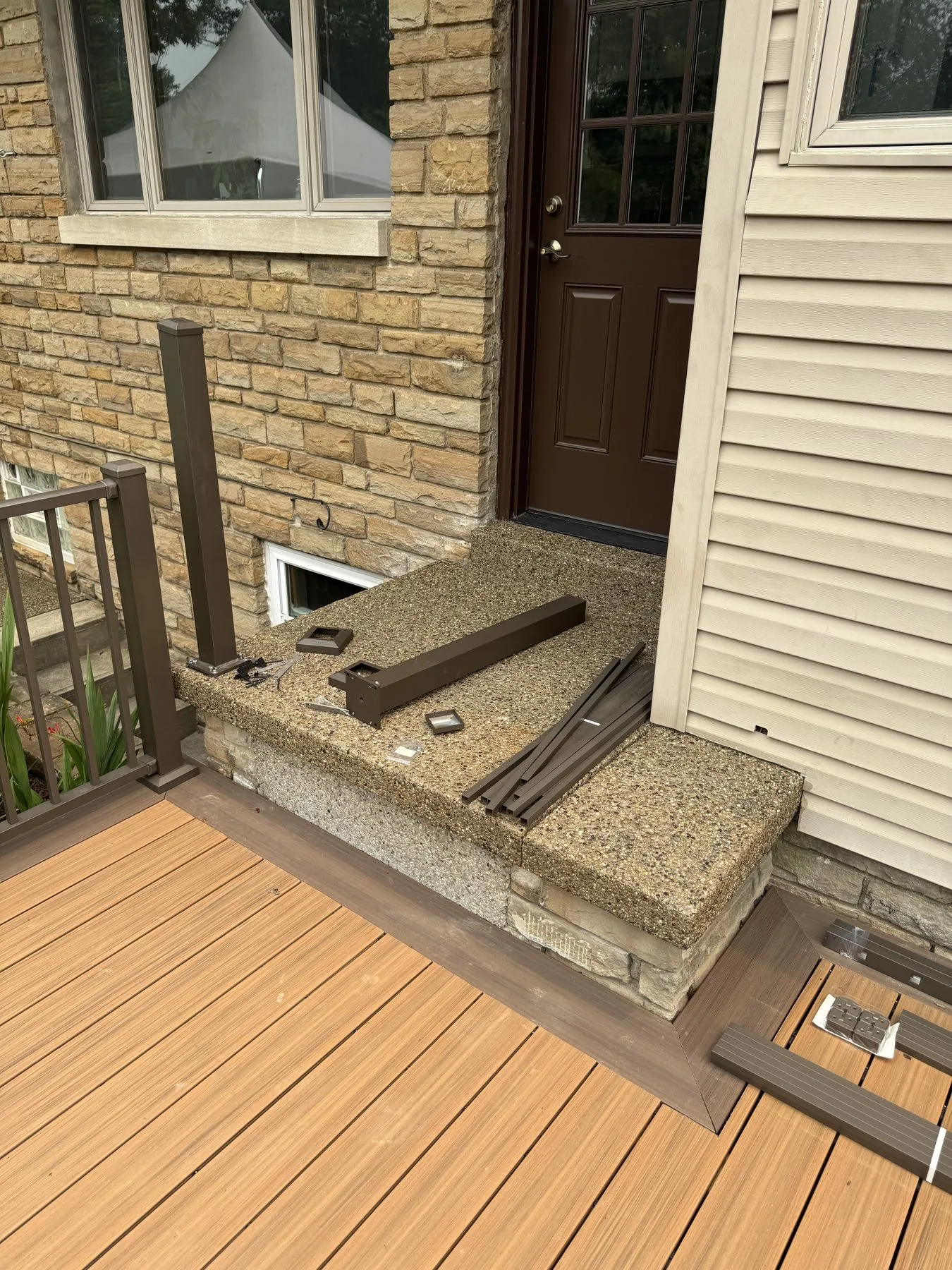 Before: post base hardware and cut aluminum rail pieces staged on the stoop