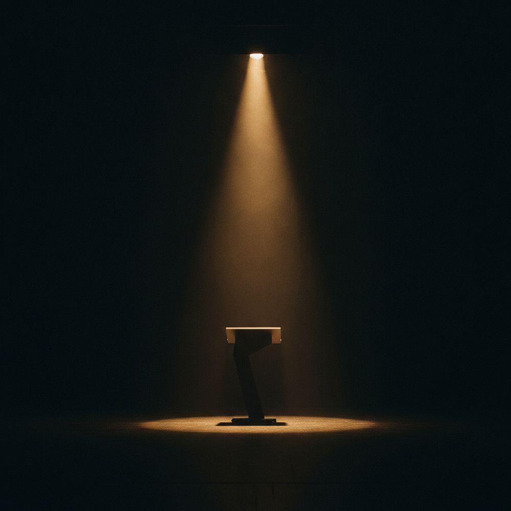 A single warm spotlight on a lectern in a dark room