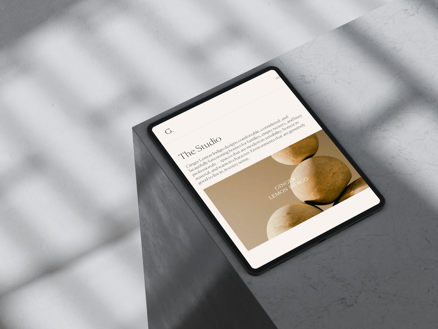 Ginger Lemon Indigo's homepage on a tablet against a marble surface, showing "The Studio" introduction section
