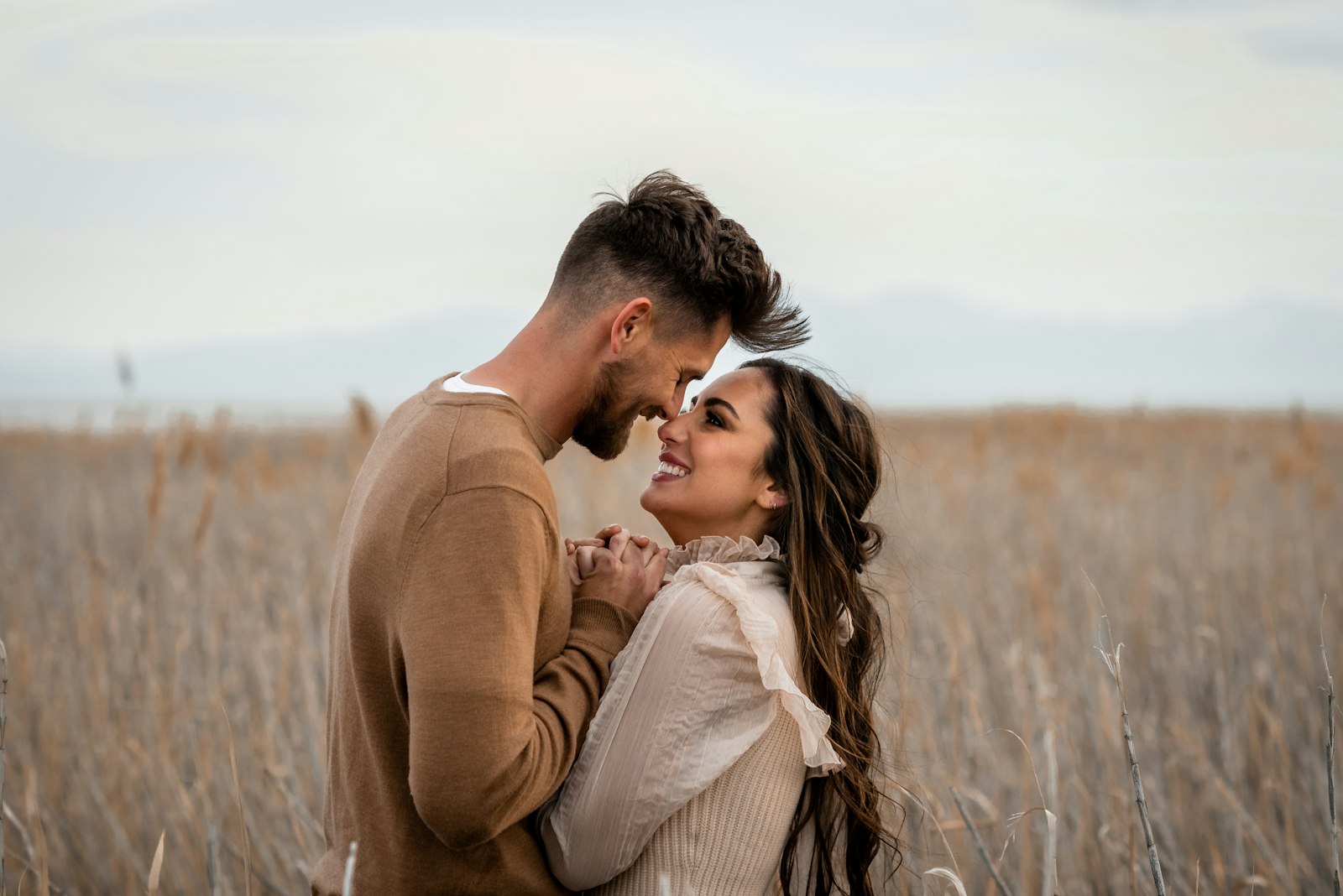 A couple leaning in close in a golden field