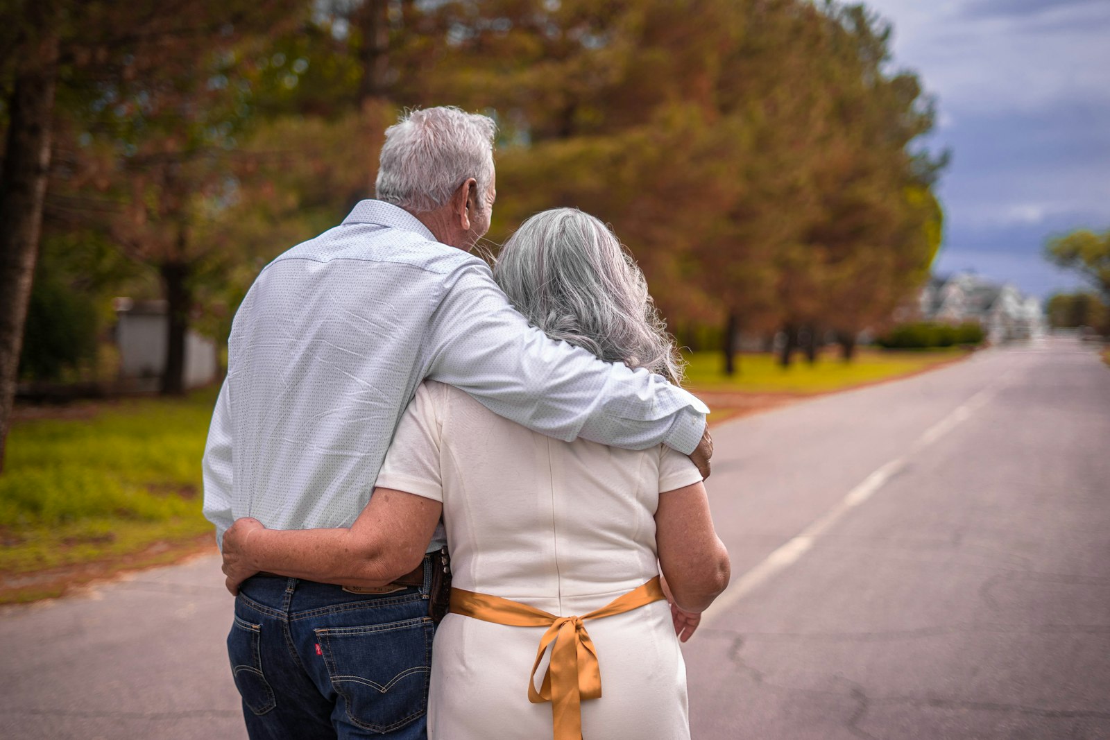 An older couple walking arm in arm down a quiet road