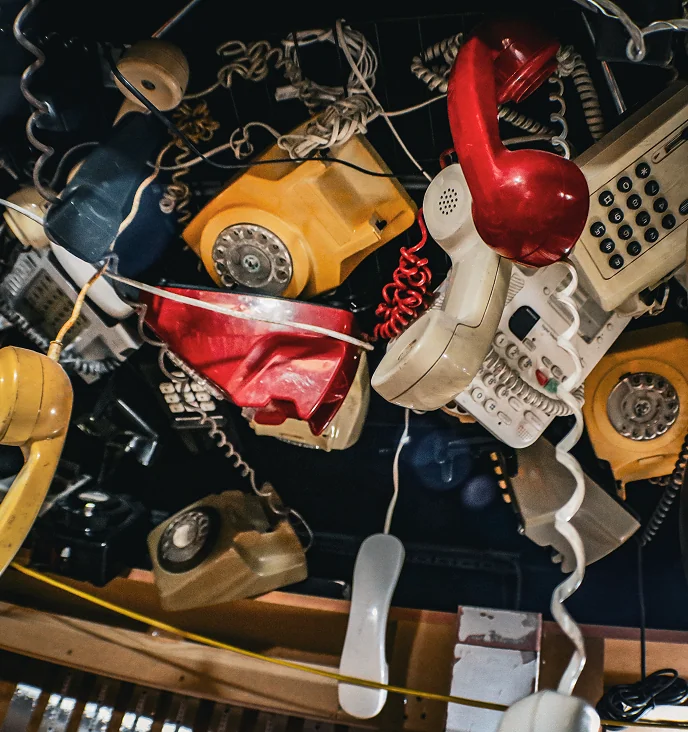 Collection of vintage telephones hanging from cords.