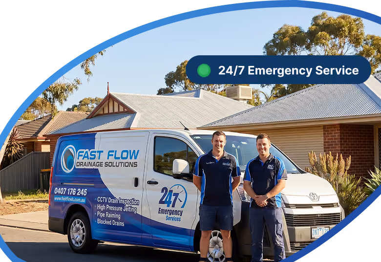 Two men in uniforms stand in front of a Fast Flow Drainage Solutions service van in a residential area.