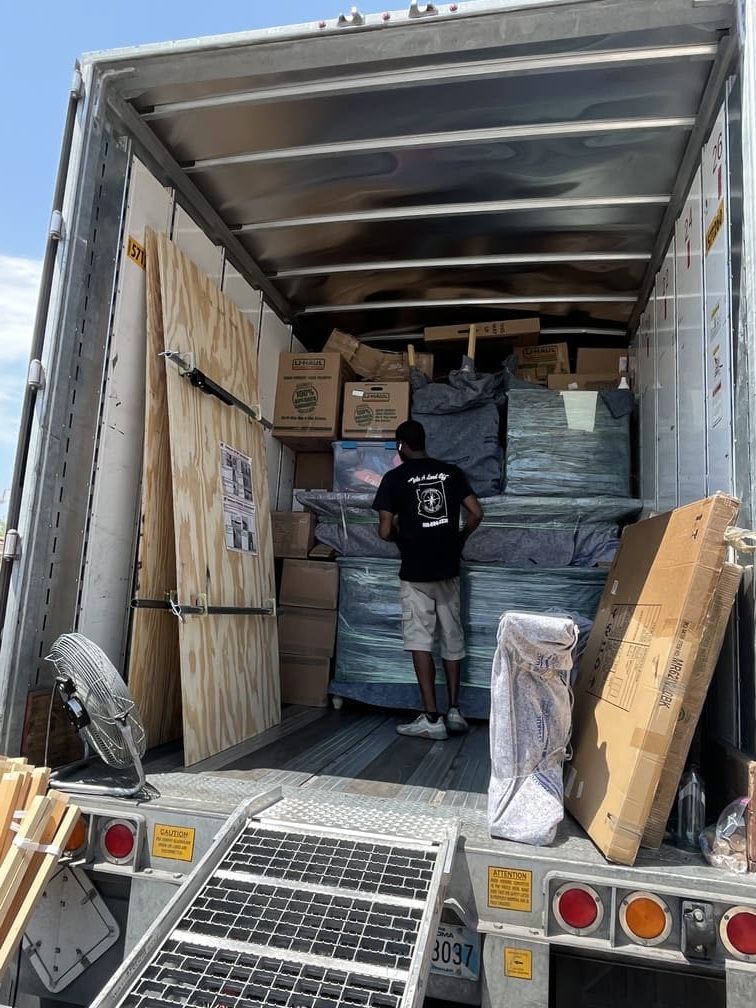 Movers shutting the doors of a fully loaded moving van, ready for transport.