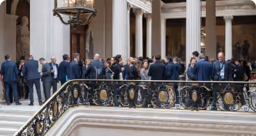 Groupe de personnes en tenue professionnelle discutant dans un bâtiment officiel à l'intérieur.