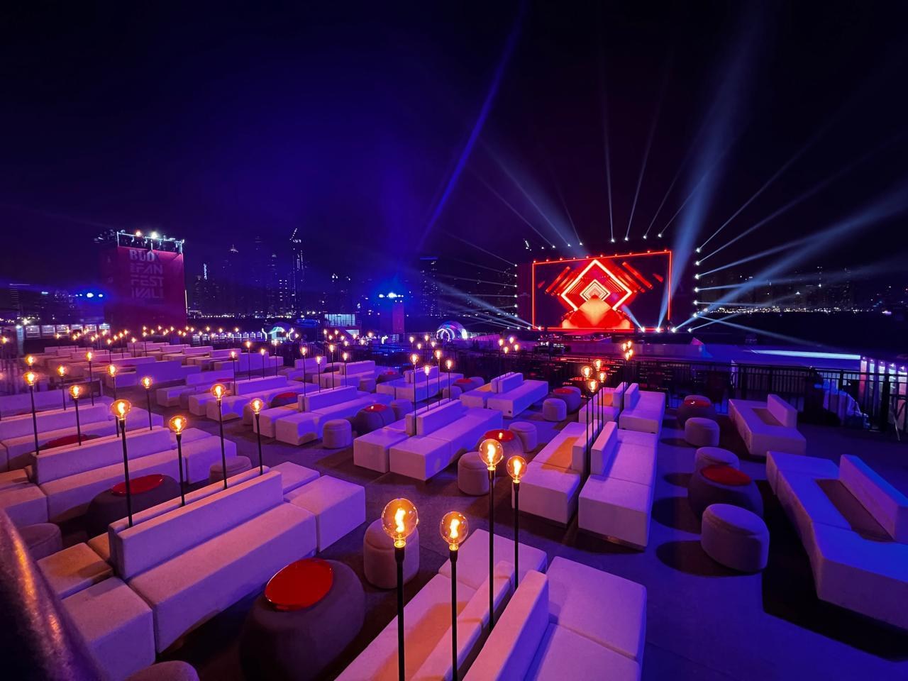 Evening fan zone lounge with white seating and stage lighting