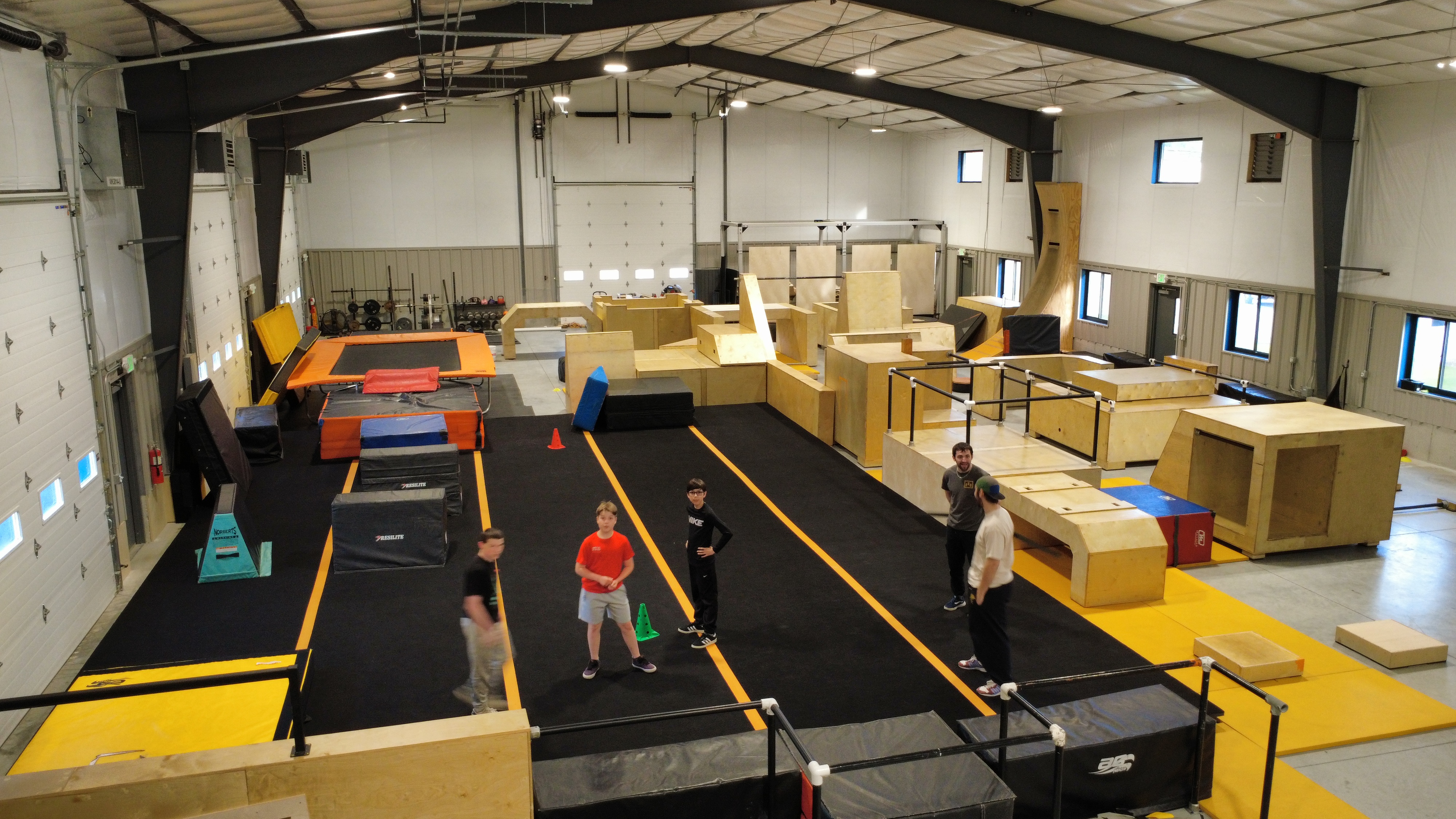 Athletes training among wooden obstacles on the main floor at HUB Parkour Norfolk.