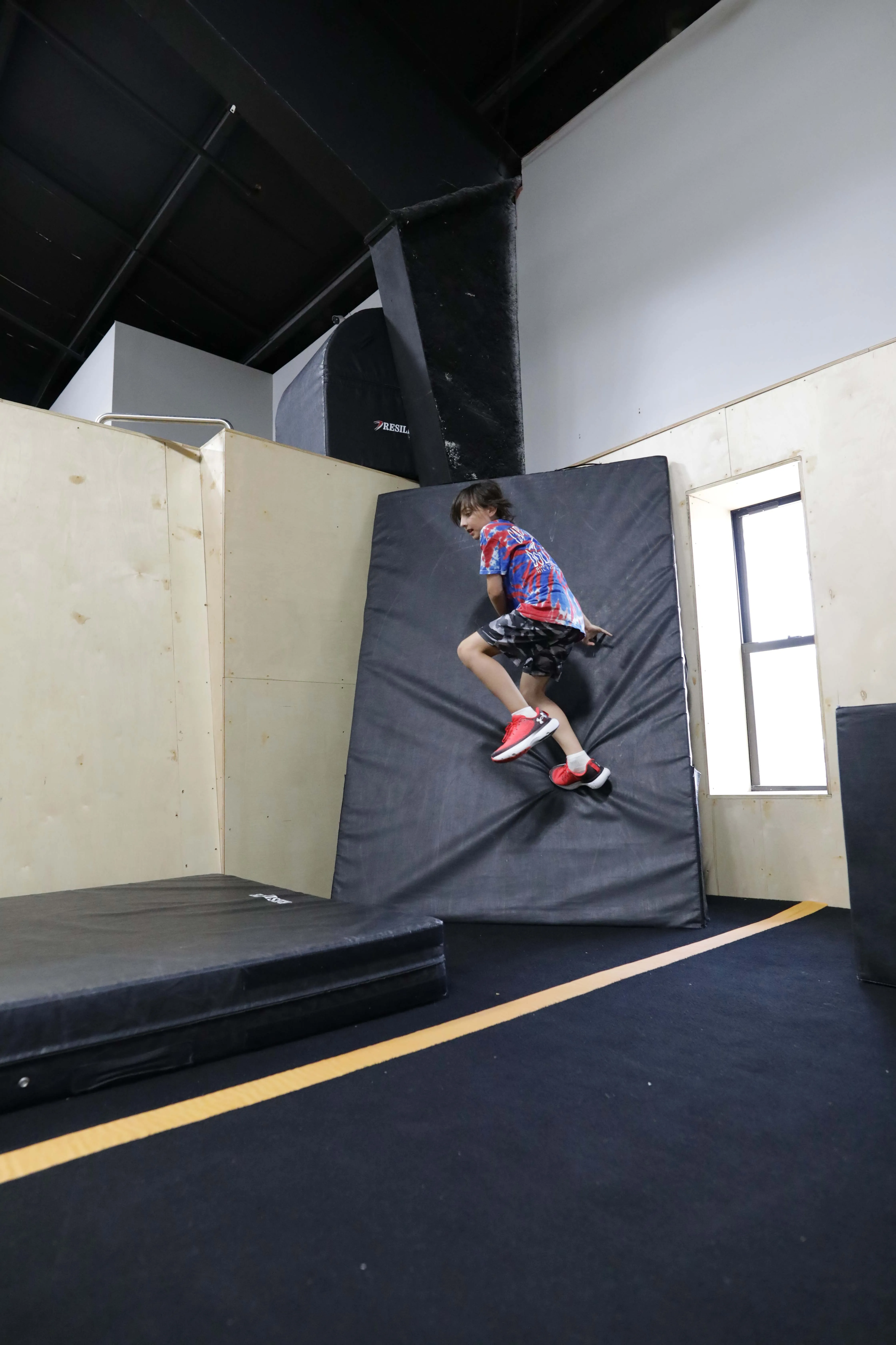 Camper practicing a wall run on a padded obstacle.