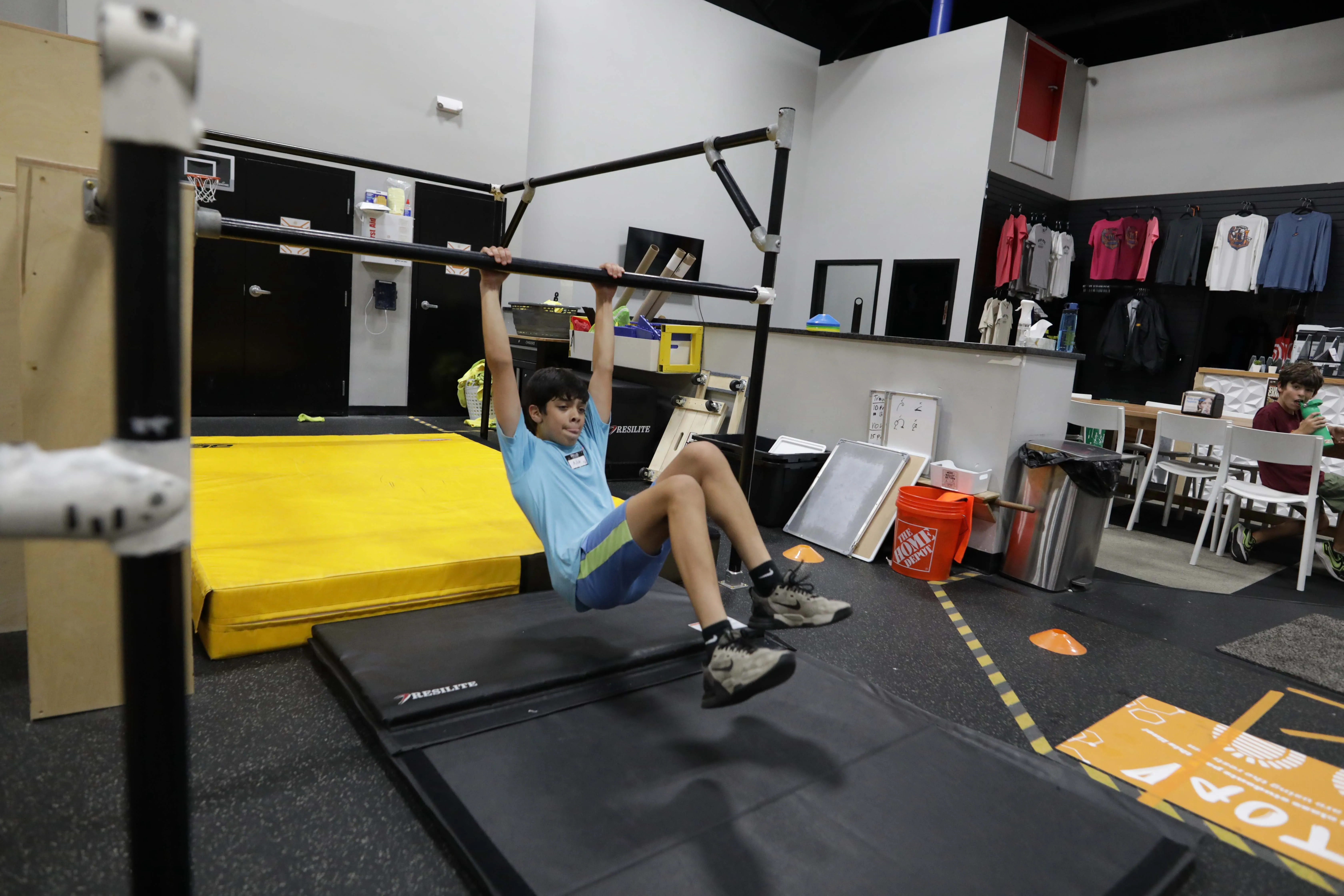Young camper practicing a bar swing over a padded landing area.