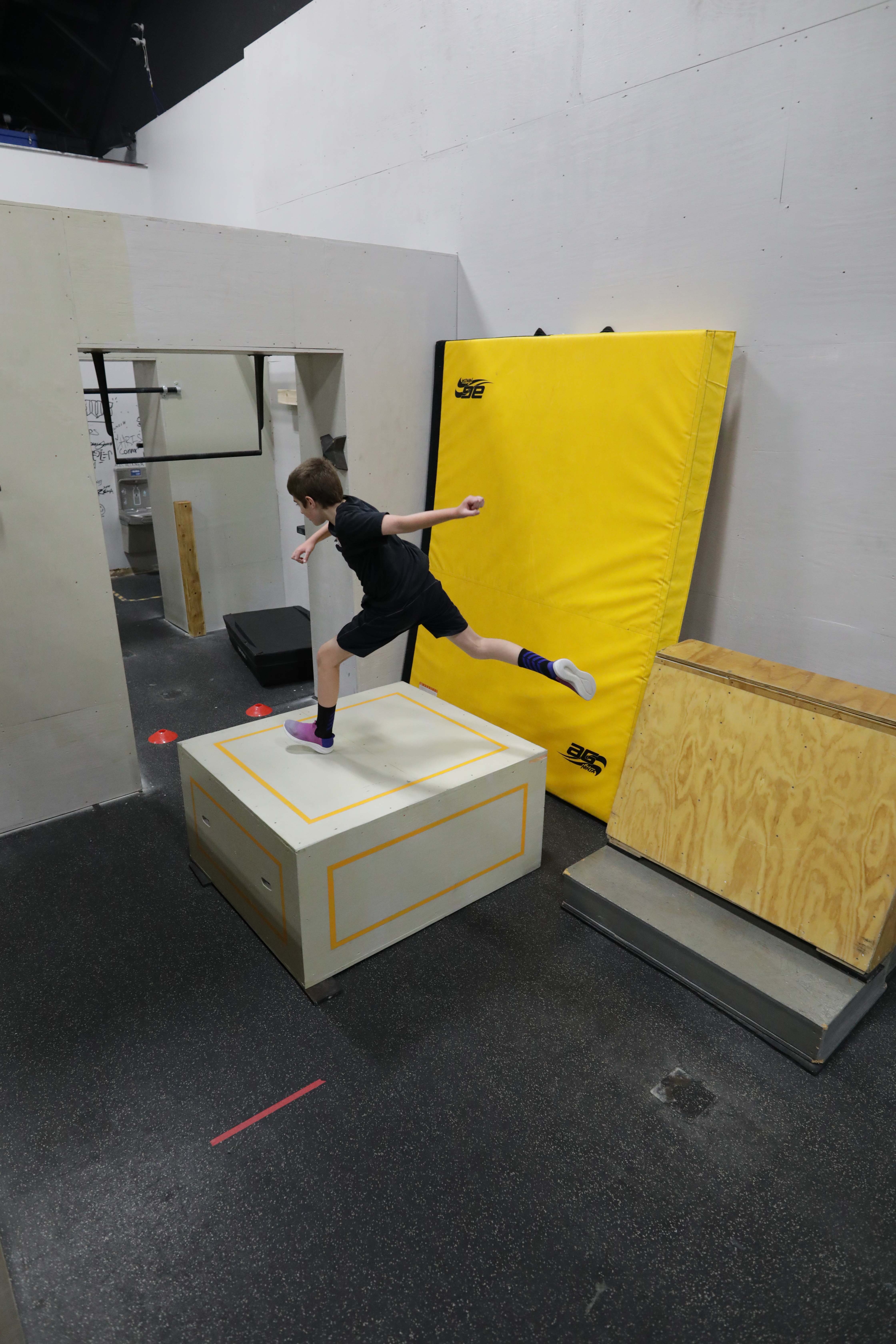 Youth athlete practicing a jump from a wooden box at HUB Parkour Sudbury.