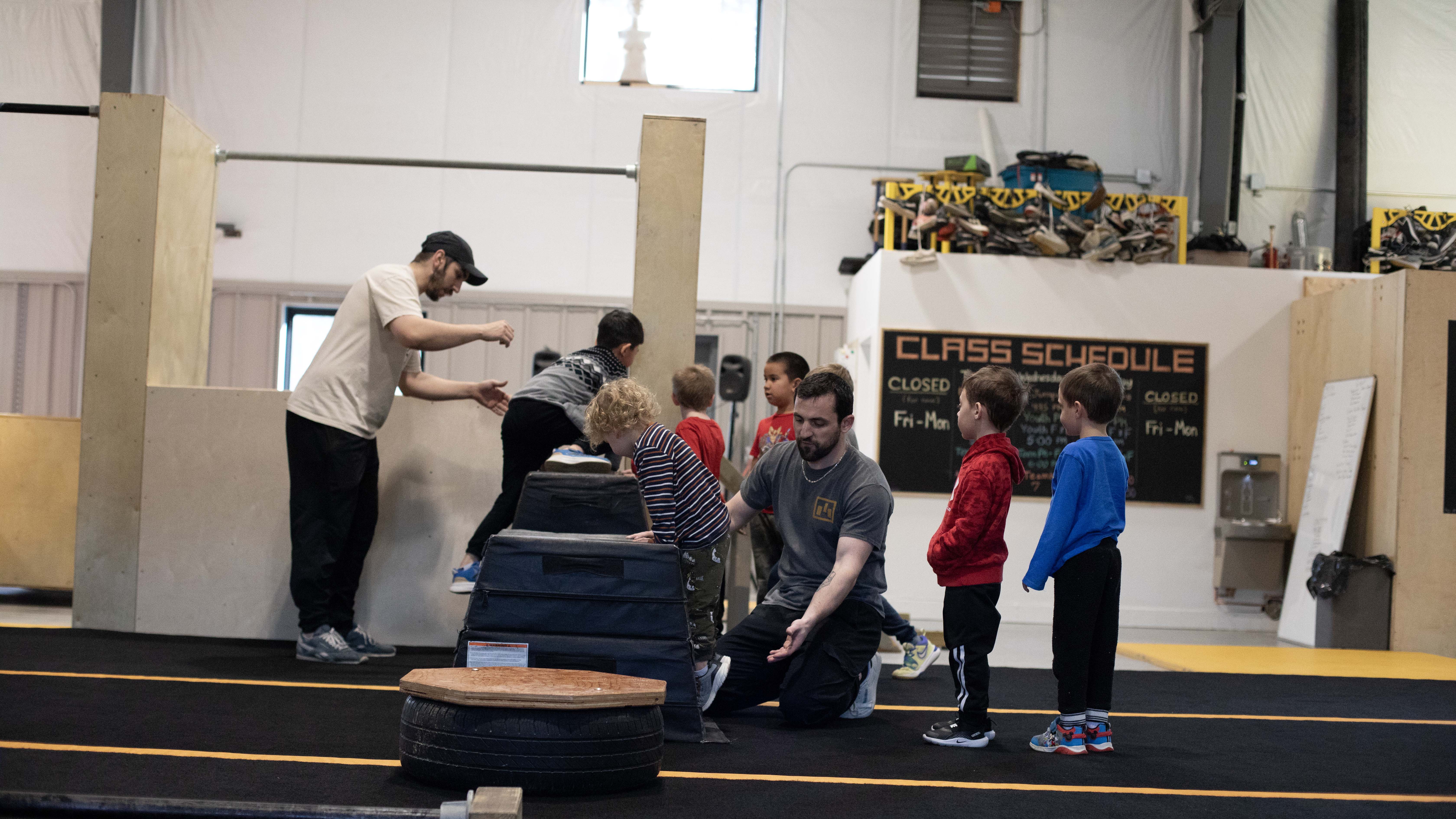 HUB Parkour coaches guiding young children through an obstacle activity.