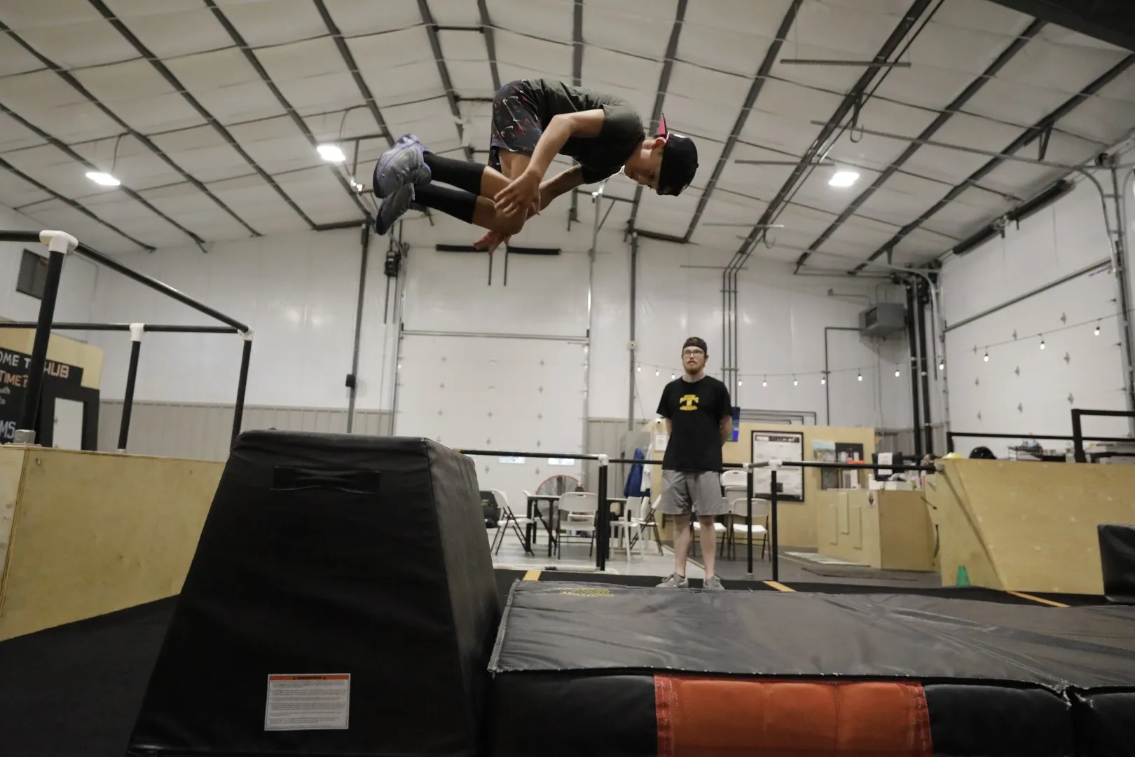 A camper flips over a mat while a coach watches