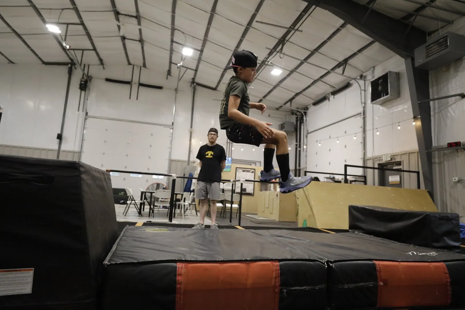 A camper jumps from a tall block onto the crash mat