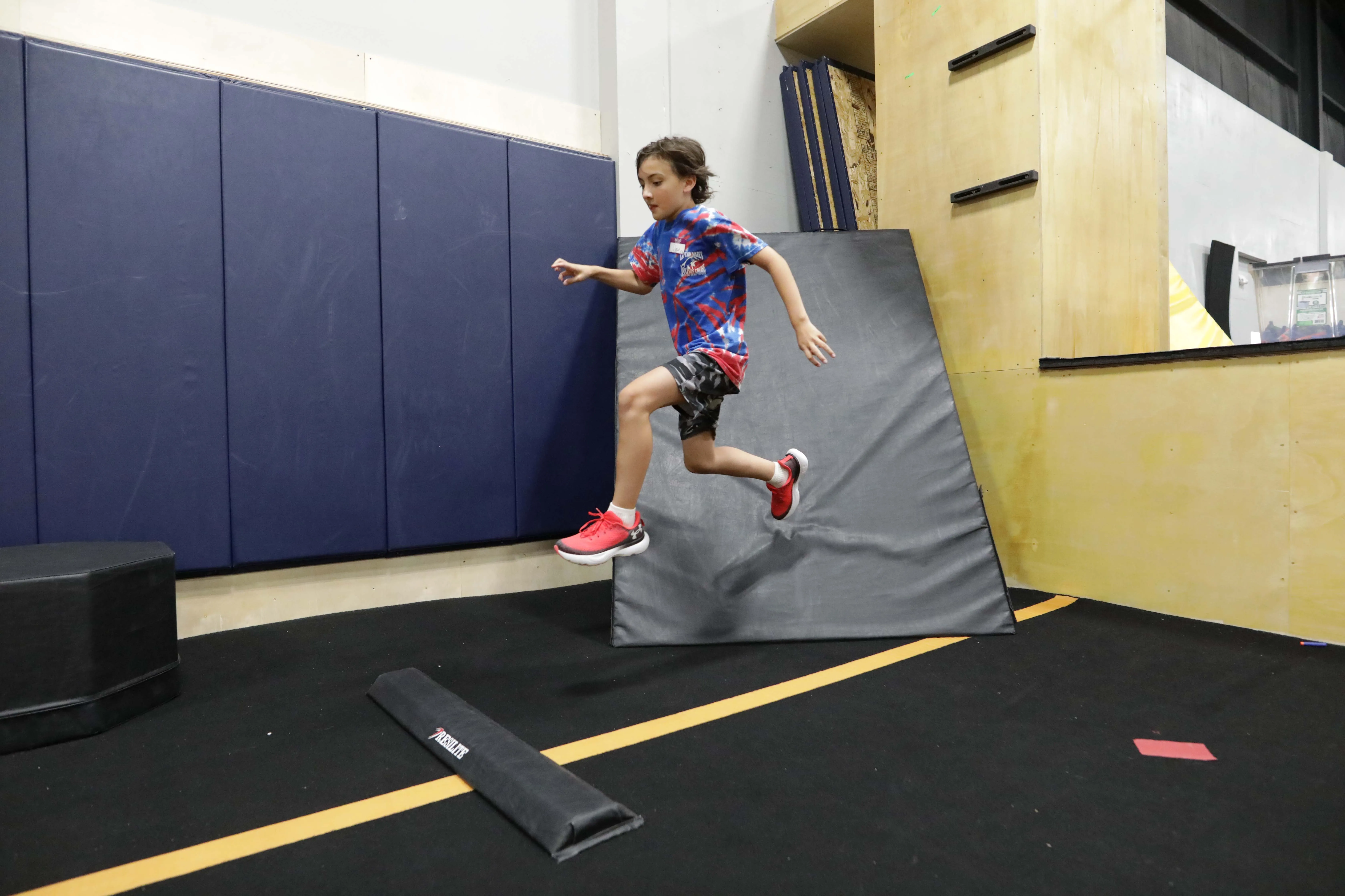 Young athlete practicing a controlled jump during class at HUB Parkour.