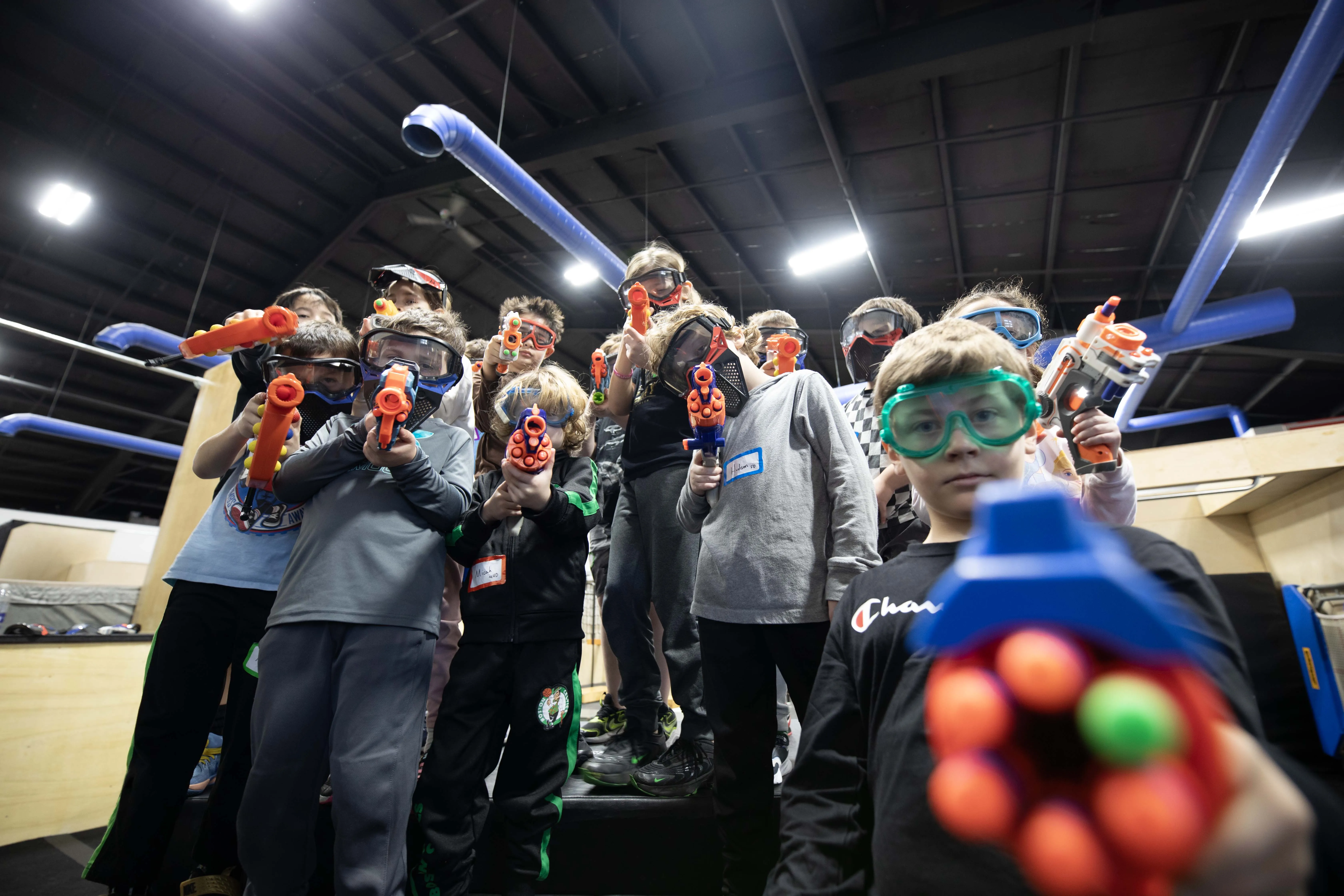 Kids in safety glasses with foam blasters at a HUB Nerf party