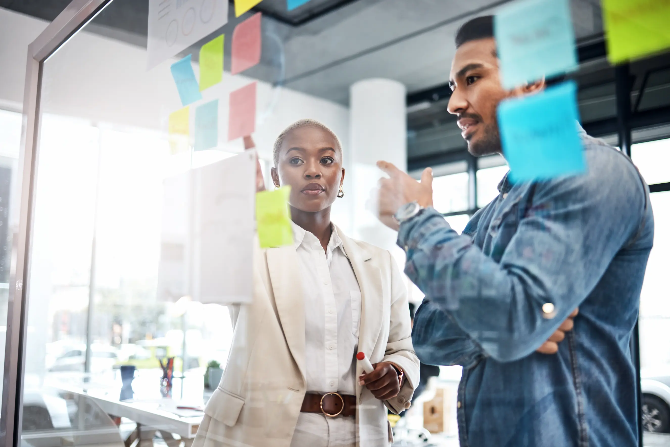 Deux développeurs échangeant devant un tableau de post-its