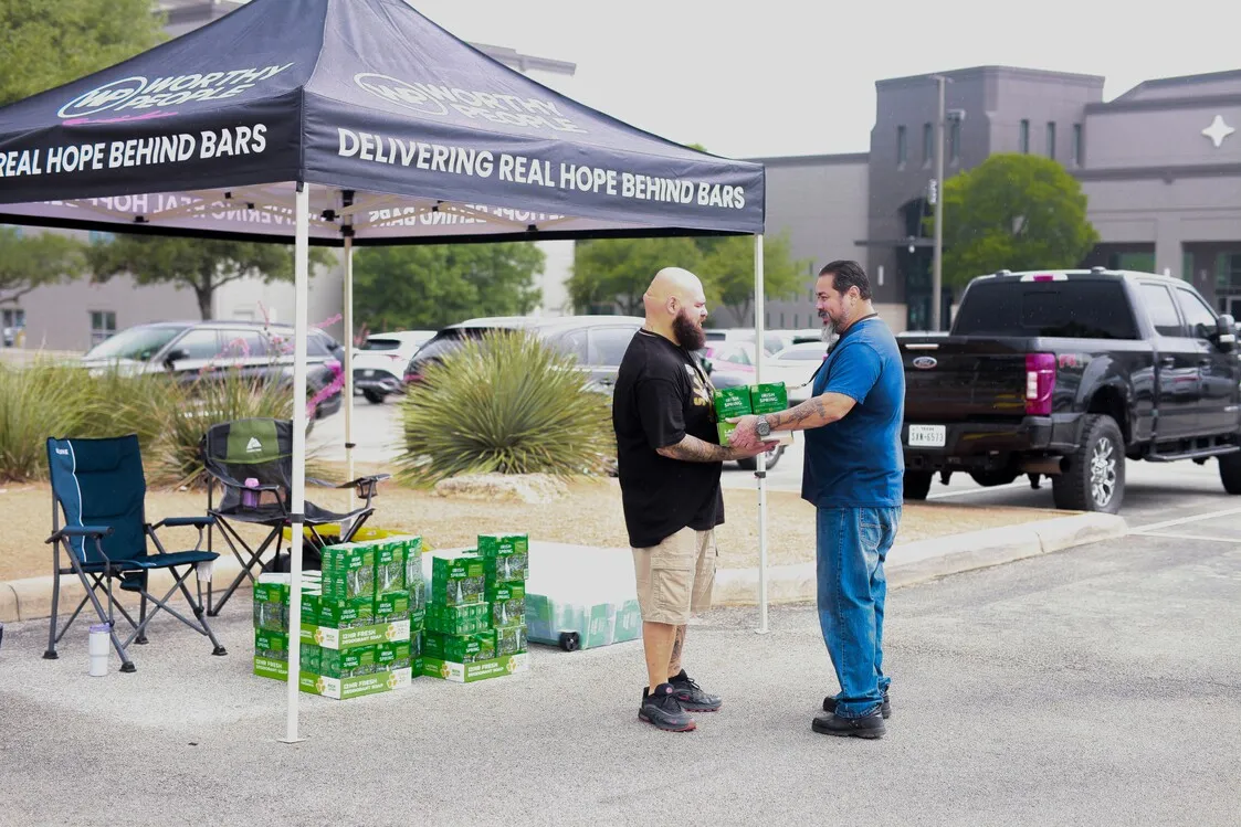 Two men at Worthy People outreach tent handing out supplies