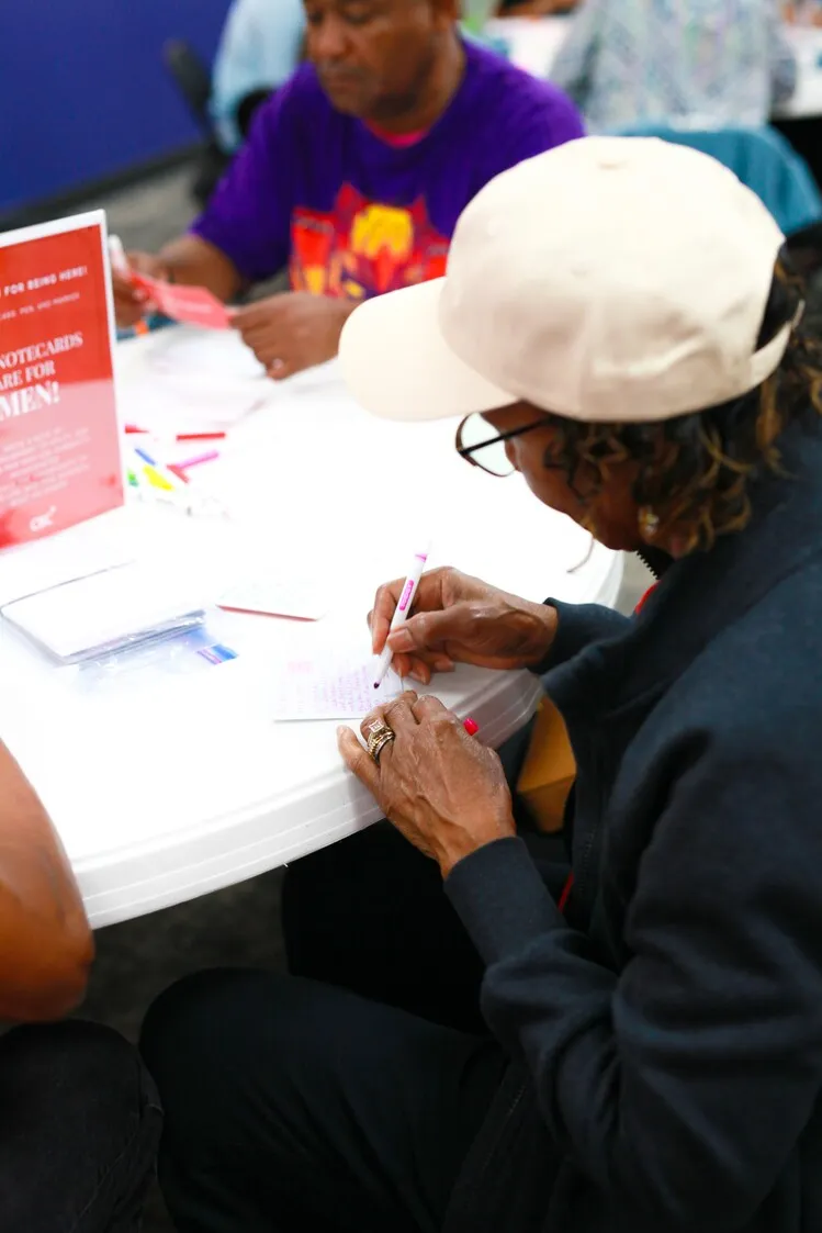 Volunteers writing encouragement notecards at event table