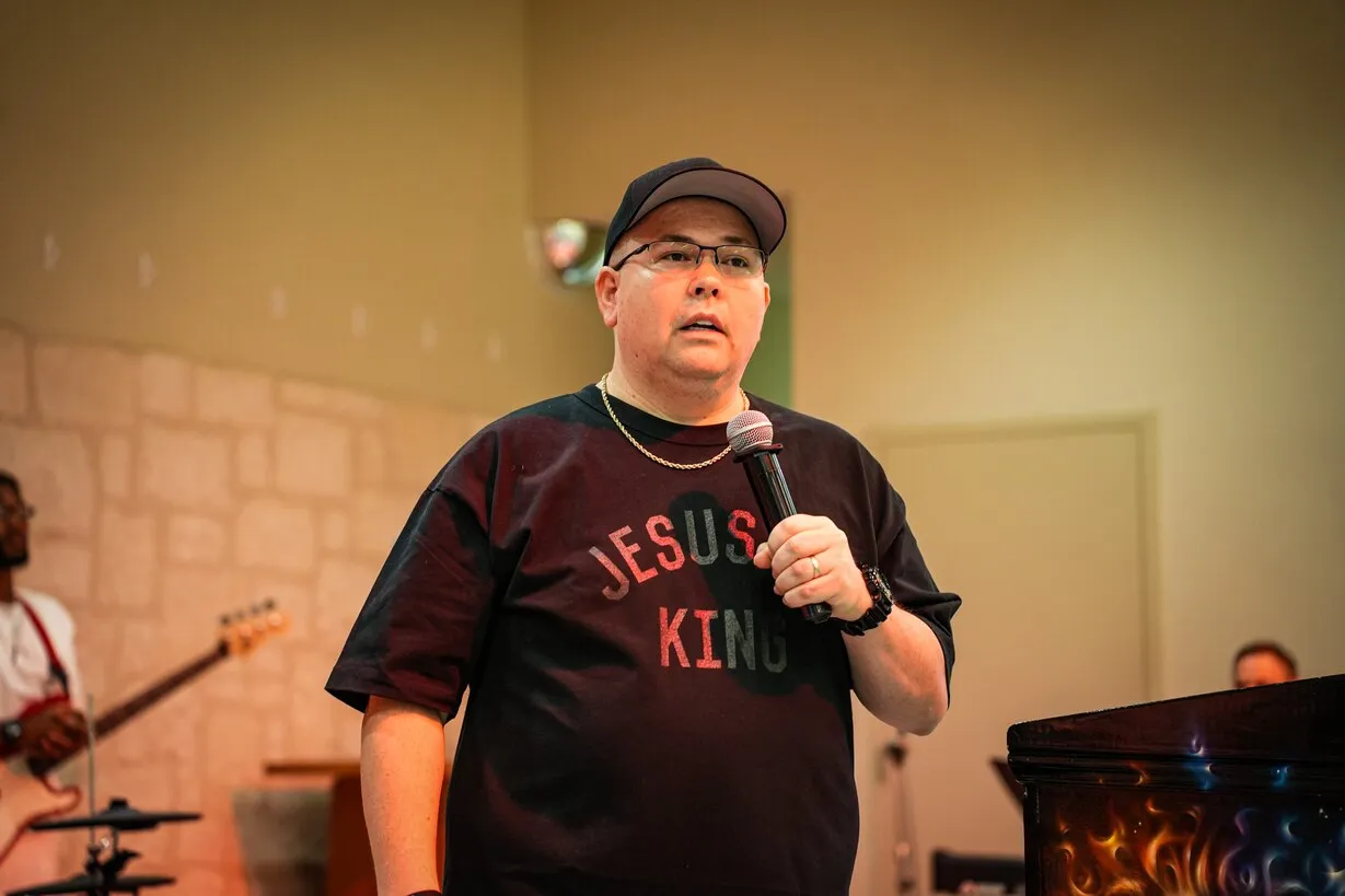 Speaker in Jesus Is King shirt preaching with microphone