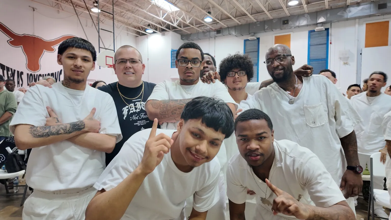 Group of inmates and volunteer posing together in gym
