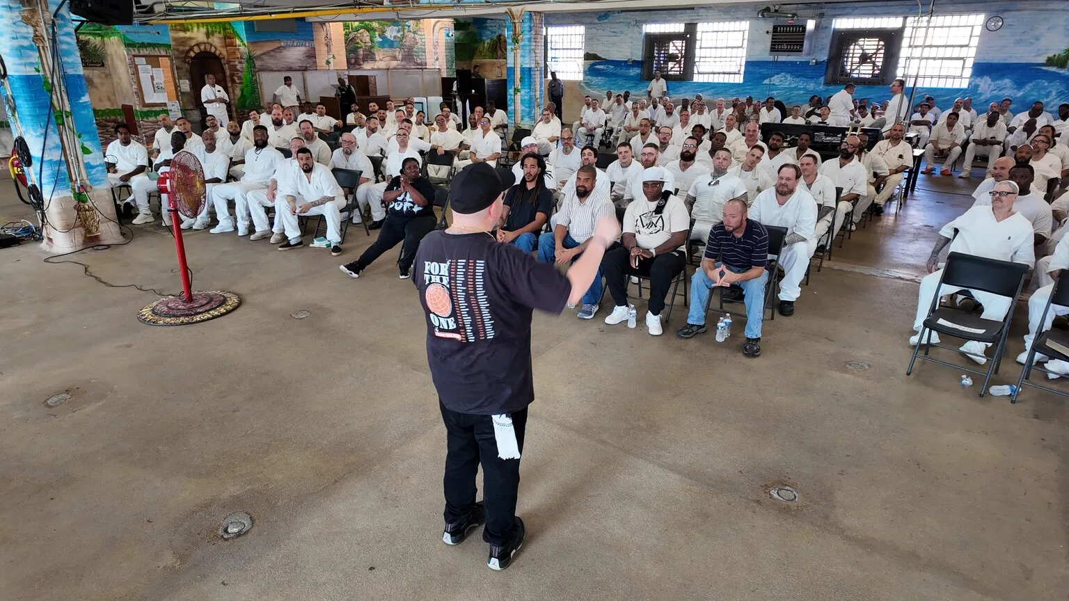 Speaker addressing rows of inmates in prison dining hall