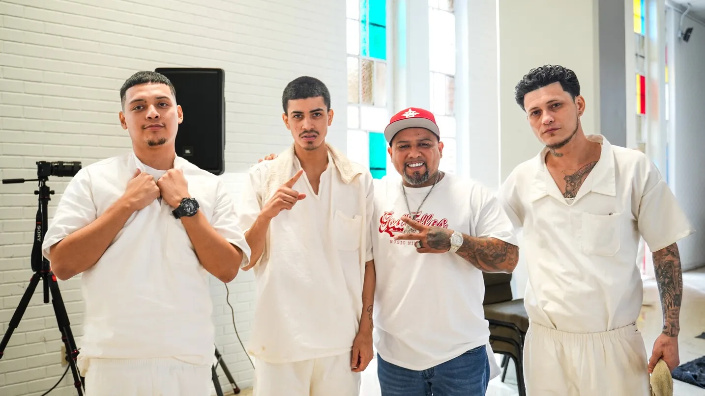 Four men in white uniforms posing together indoors