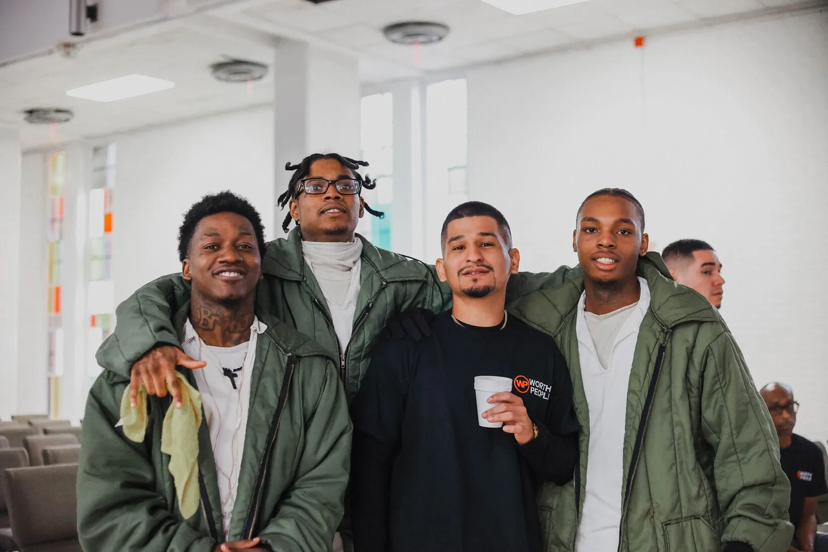 Four men in green jackets smiling together indoors