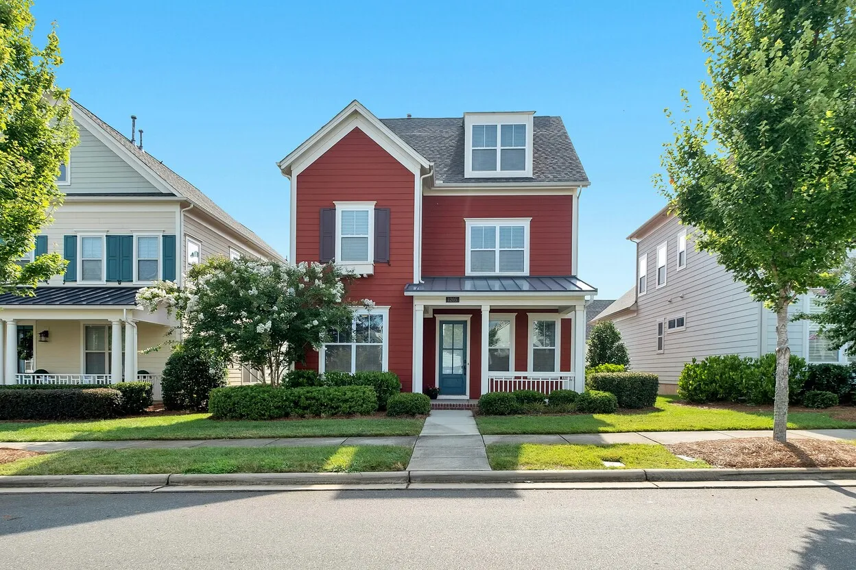 Red two-story house with front porch on residential street