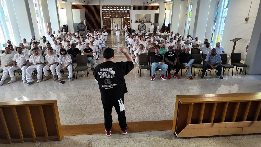 Speaker addressing rows of inmates in prison chapel